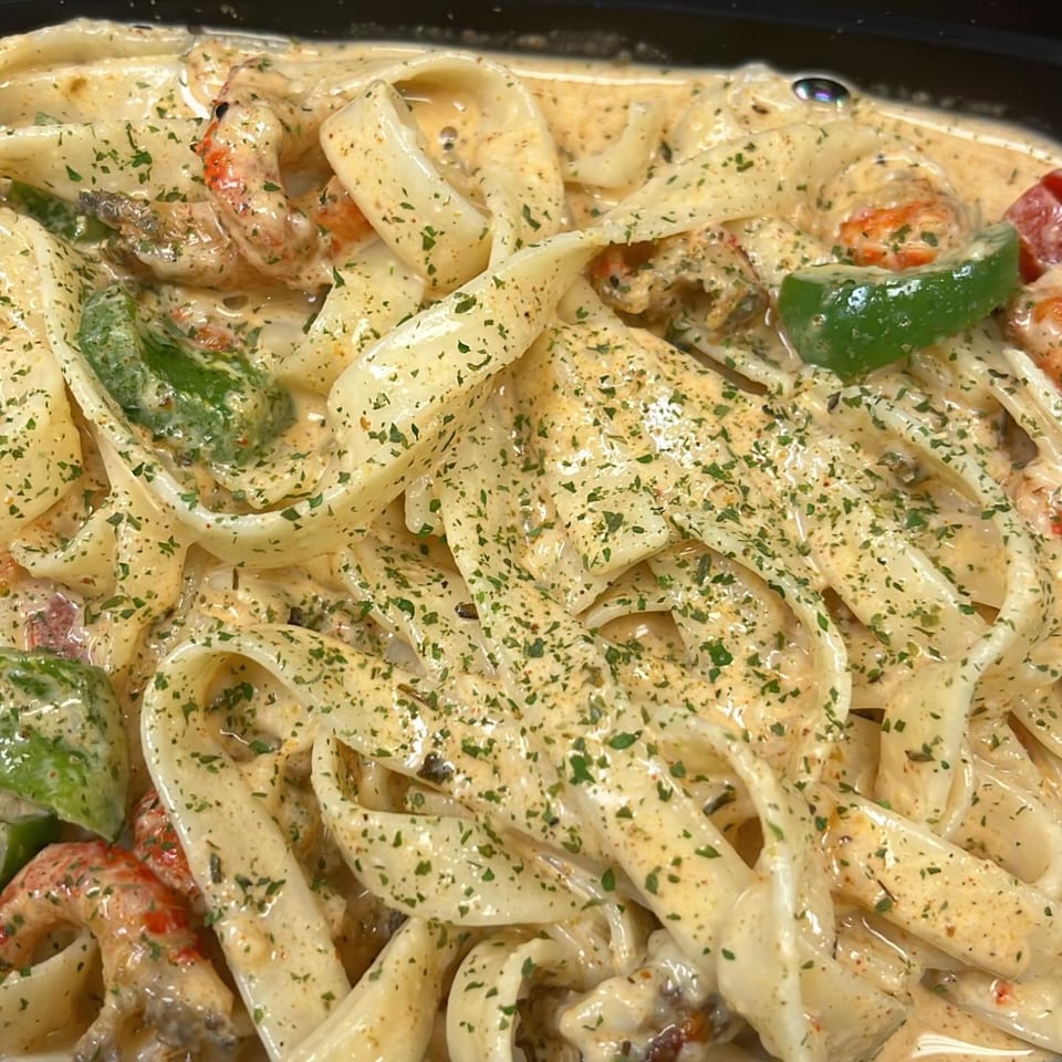Creamy seafood pasta with fettuccine, shrimp, green bell peppers, and parsley from Lutfi’s Raymore.